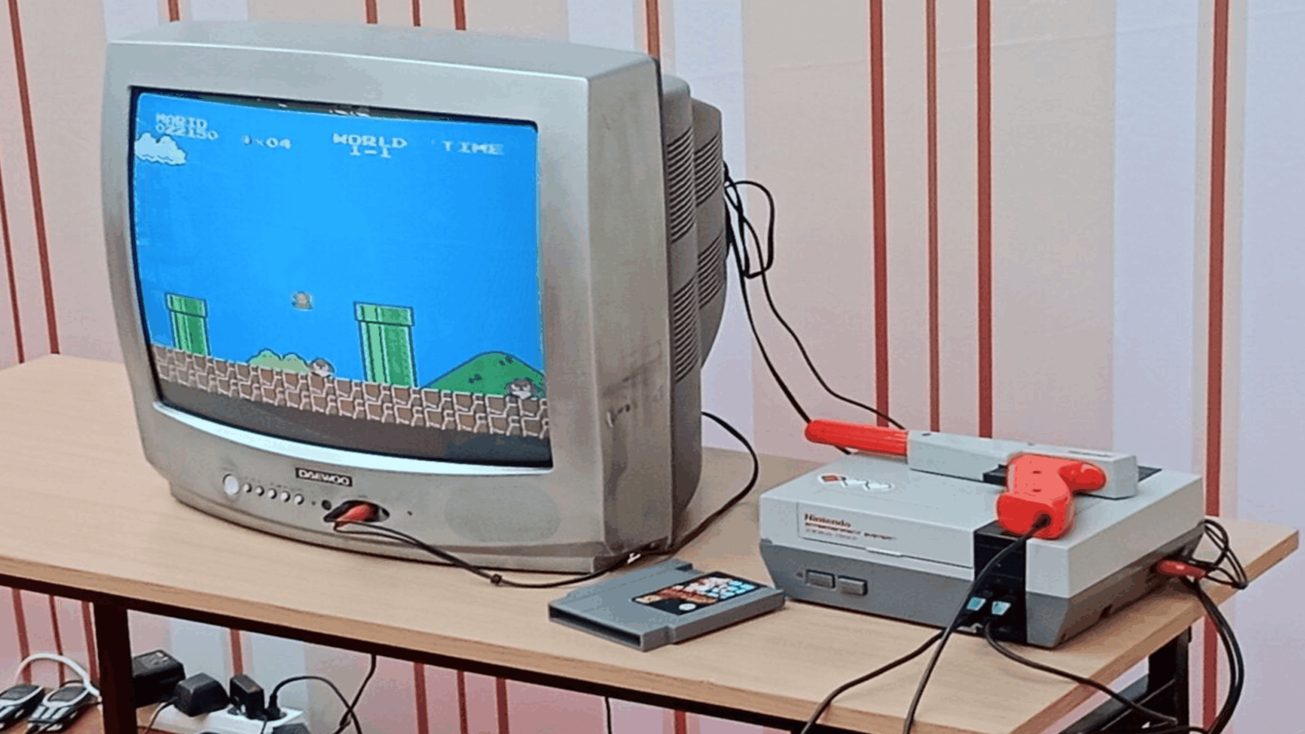 A CRT TV displays Super Mario Bros. gameplay. Classic consoles, including an original Nintendo Entertainment System and a Zapper gun, sit nearby on a wooden table, with cables connecting the devices.