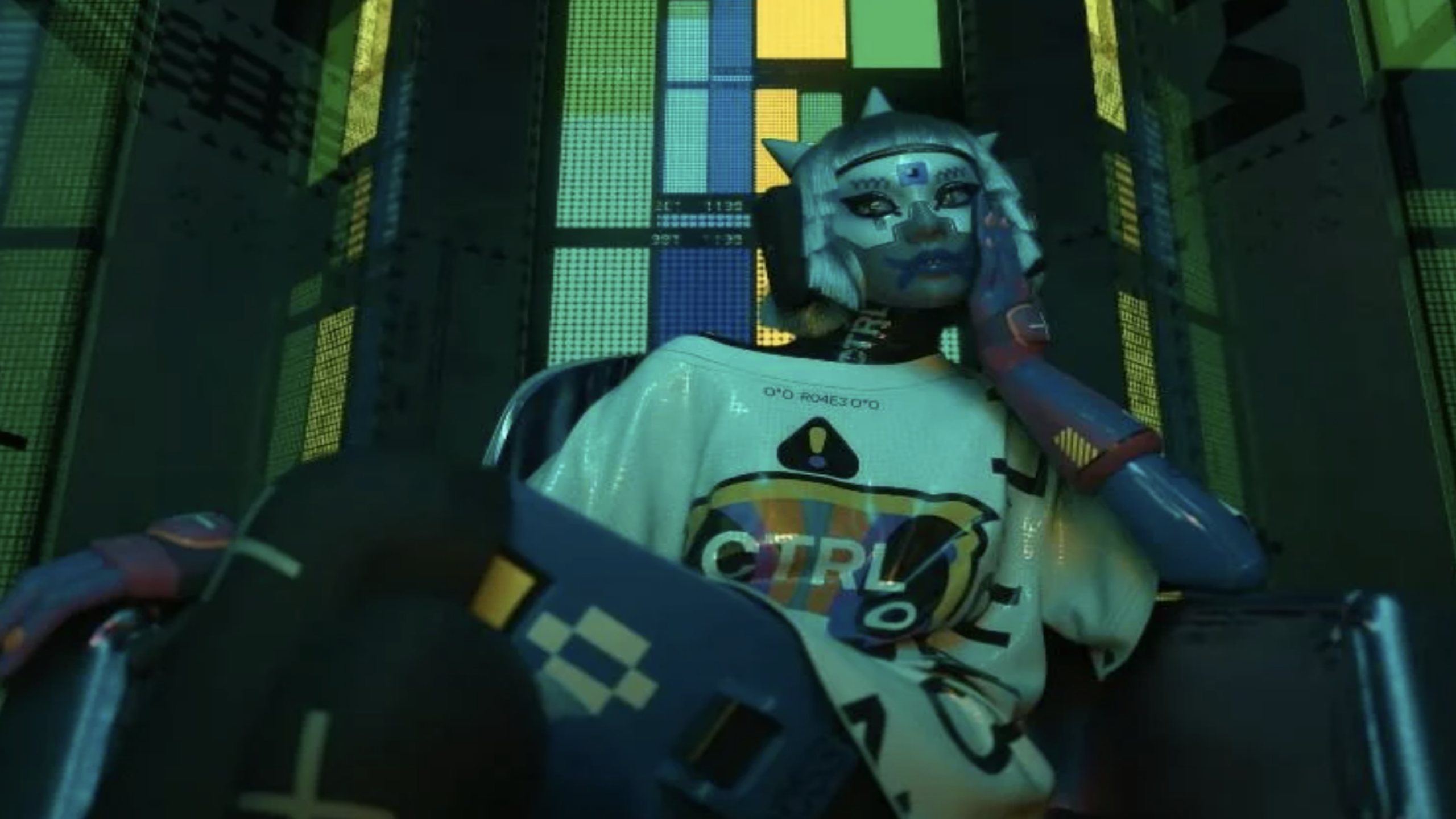 A person in futuristic, robot-inspired makeup and attire sits in a chair, wearing a shirt with "CTRL" on it, against a backdrop of colorful, illuminated panels—evoking the dynamic energy of Physical Games.