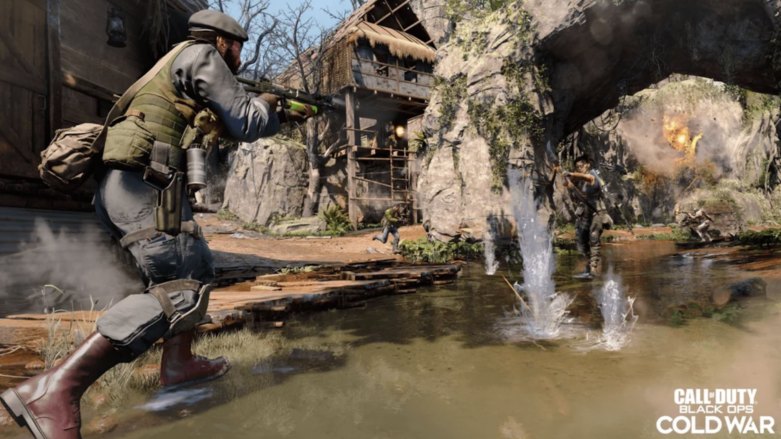 A soldier aims a rifle while standing in shallow water, engaging enemies near a rustic building and stone bridge, with explosions and gunfire erupting around him. "Call of Duty: Black Ops Cold War" logo is in the bottom right corner, evoking the intense action fans also expect from games like GTA VI.