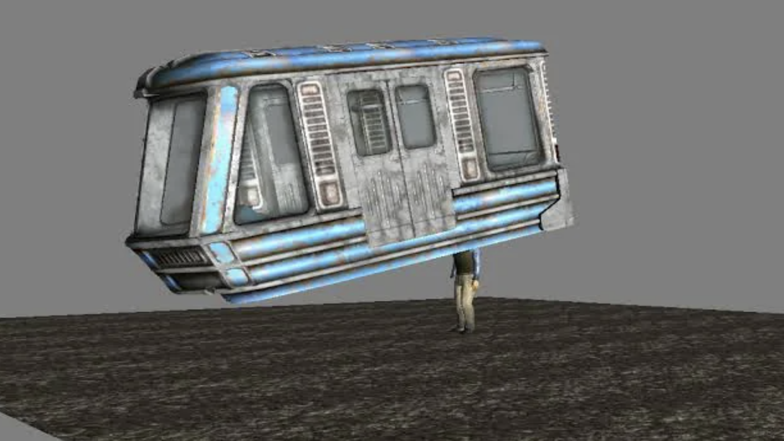 A person stands under and appears to support a large, weathered, blue and gray train car on a textured ground with a plain gray background, evoking the dramatic atmosphere of a video game scene.