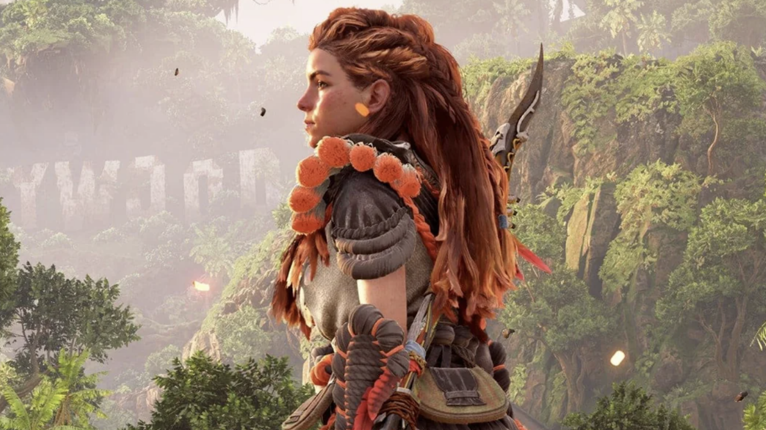 A woman with braided red hair and detailed armor stands outdoors, surrounded by lush green foliage and mountains, looking determinedly into the distance as if preparing for challenging physical games ahead.