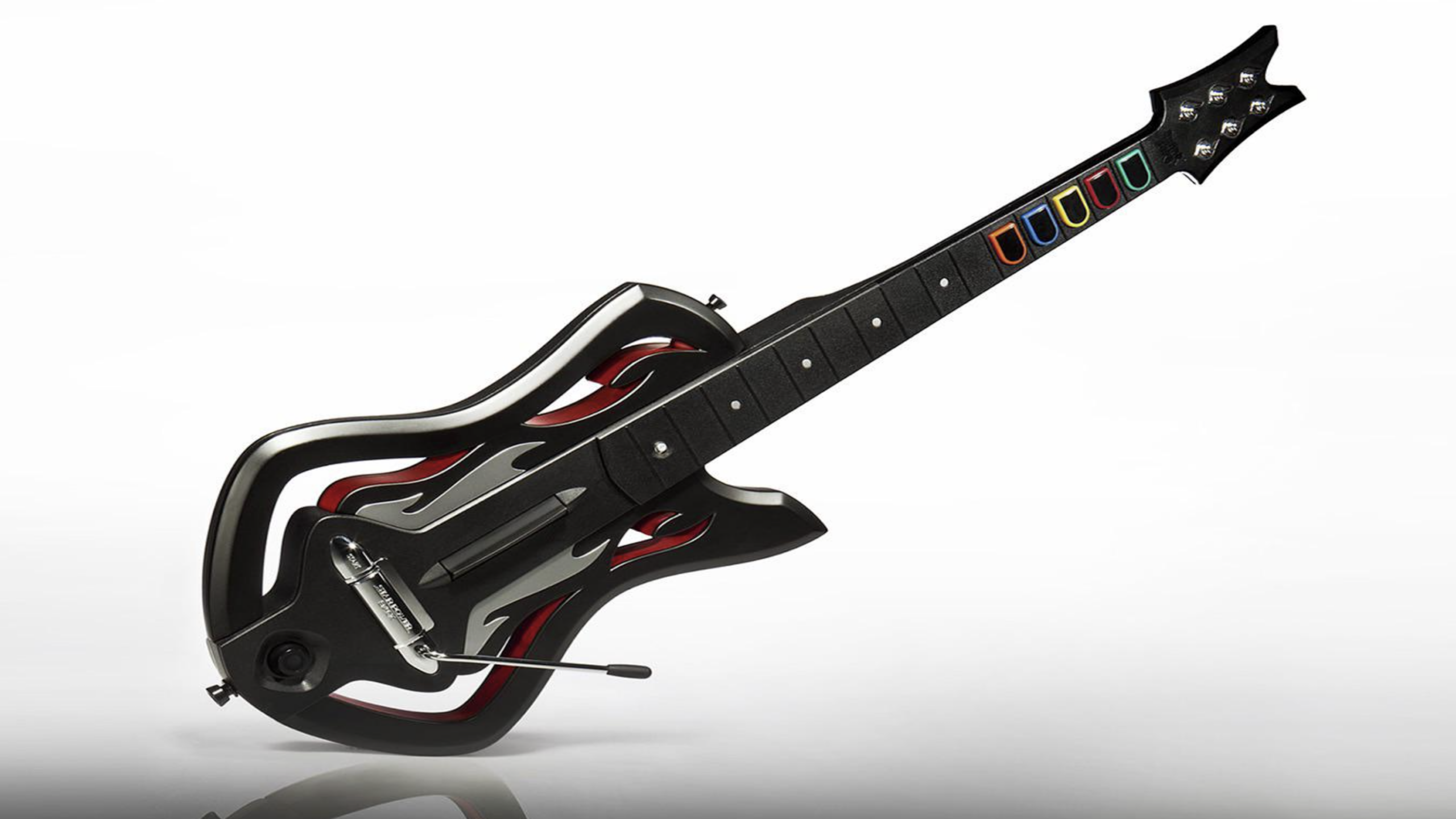 A black video game guitar controller with flame-like red accents, colored fret buttons, and a whammy bar—perfect for uncovering Video Game Secrets—set against a white background.