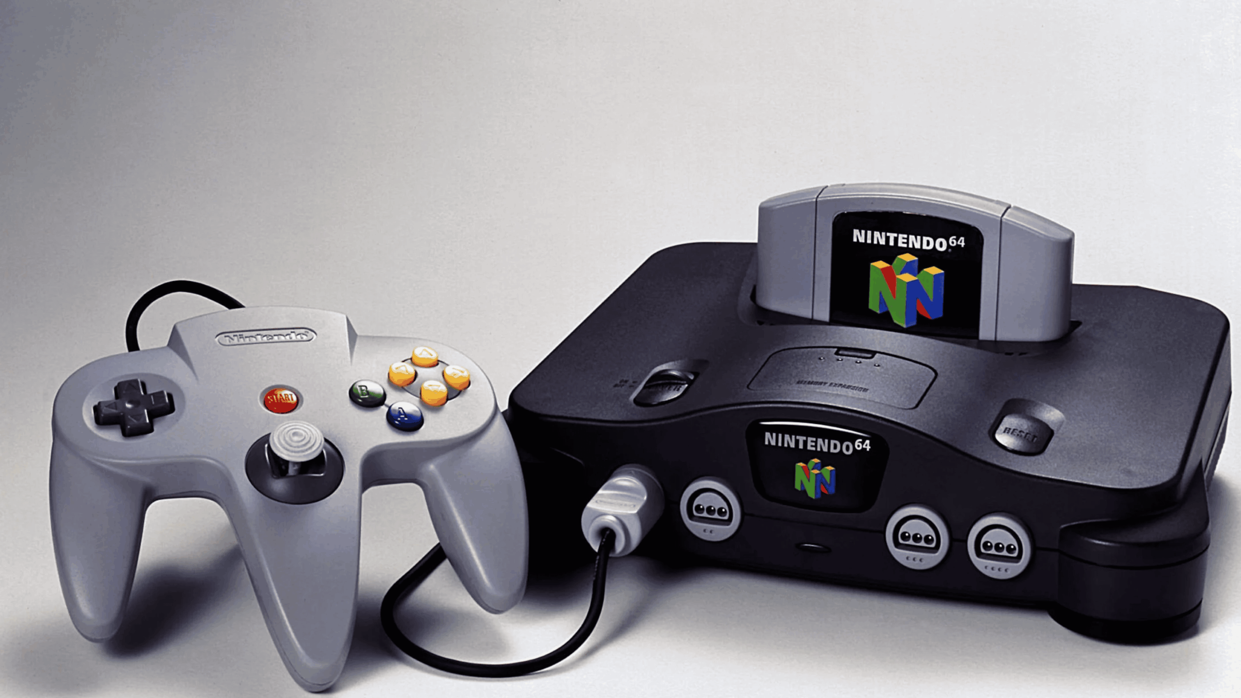 A classic example of Nintendo Consoles, this Nintendo 64 video game console features a cartridge inserted and a gray controller connected, displayed on a plain surface.