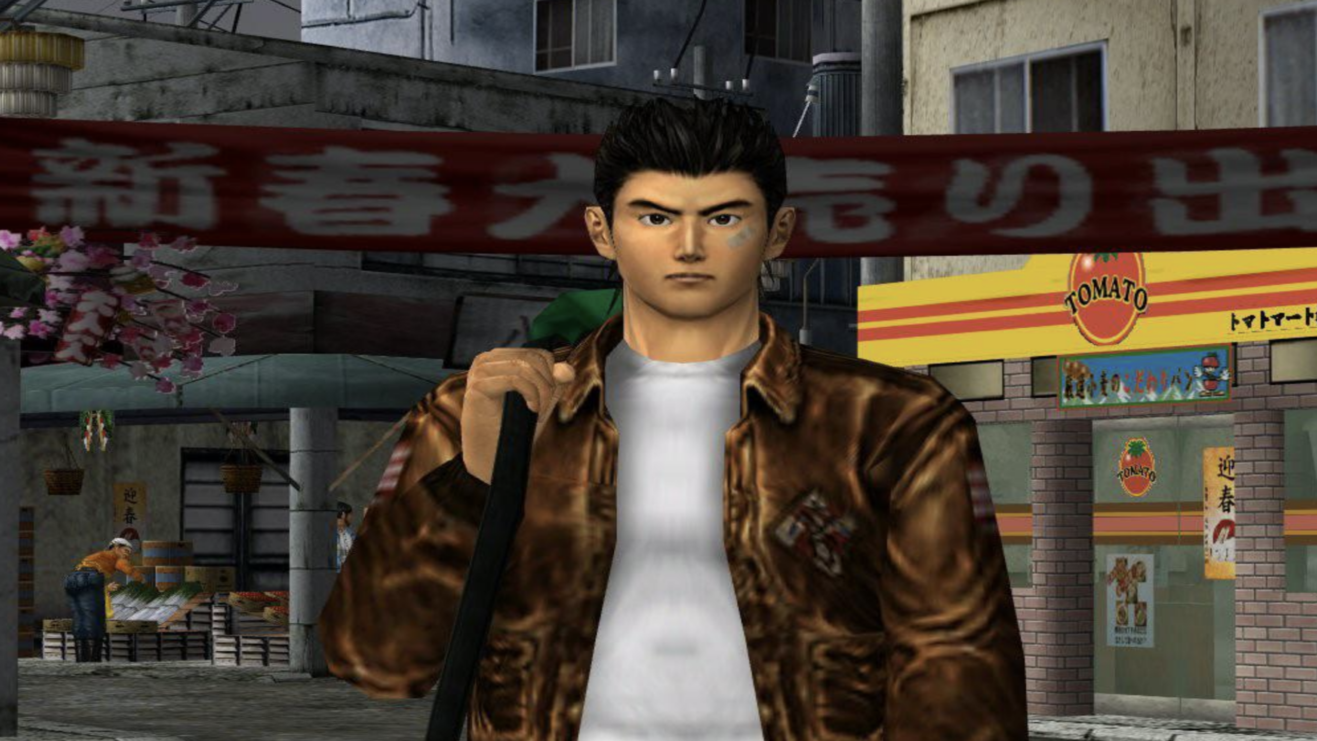 A young man in a brown leather jacket stands in an urban street, with shops, banners with Japanese text, and a building labeled "Tomato" behind him—perhaps he’s searching for rare or expensive games hidden among the bustling storefronts.