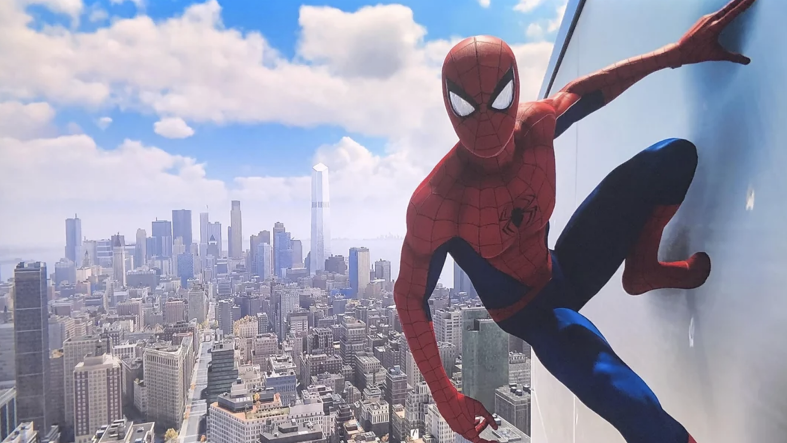Spider-Man clings to the side of a tall glass building, his iconic suit standing out against a clear blue sky and a city skyline filled with towering skyscrapers in the background.