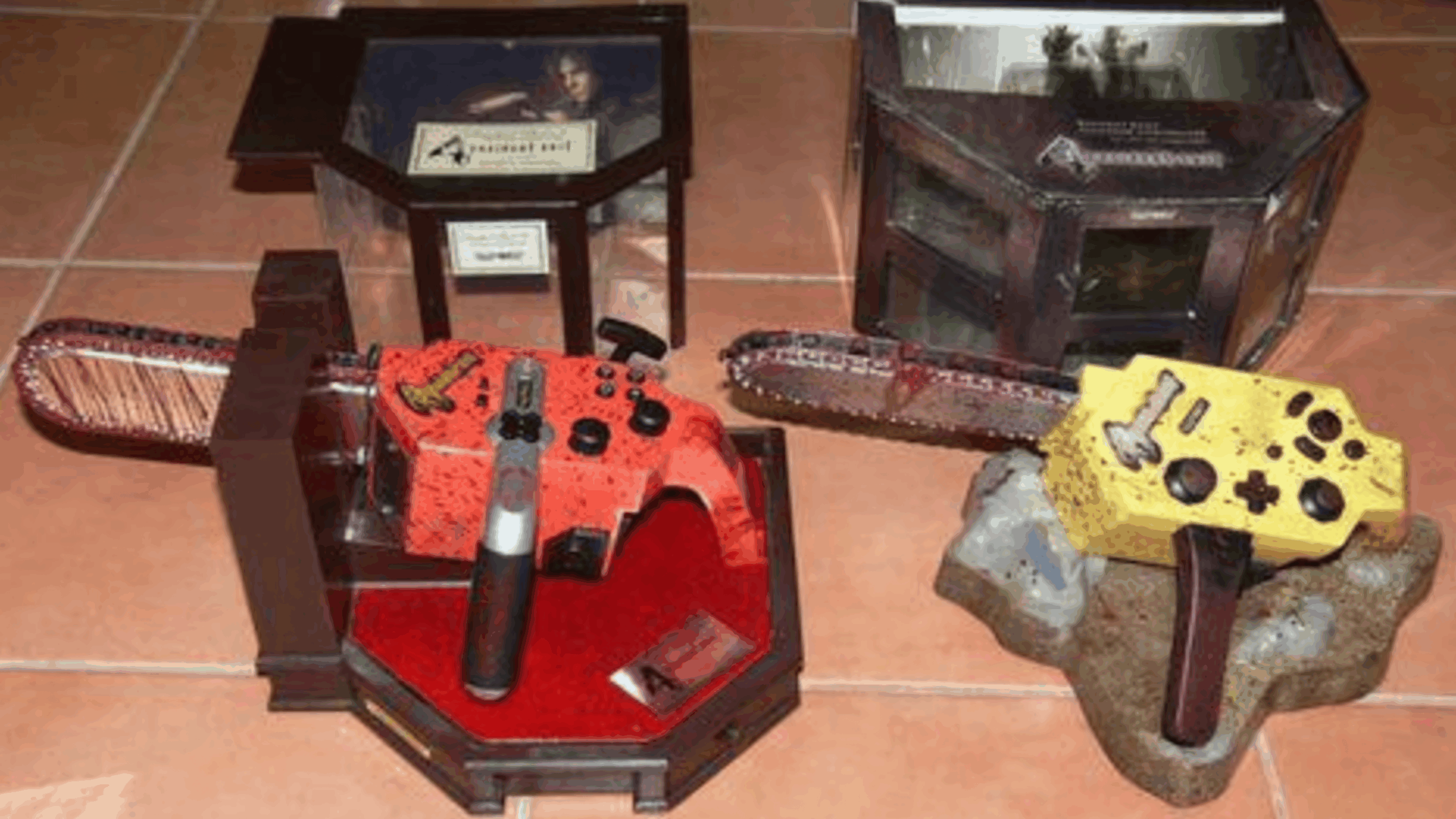Two video game controllers shaped like chainsaws, one red and one yellow, are displayed in decorative cases with Resident Evil branding on a tiled floor. These unique gaming accessories are showcased alongside plexiglass cases and Resident Evil boxes visible in the background.