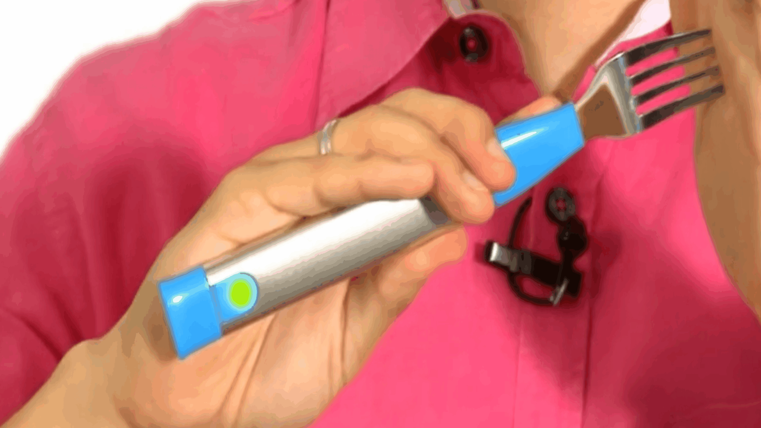 A person in a pink shirt holds a large blue and silver electronic fork—one of the latest tech gadgets—near their mouth, preparing to eat.