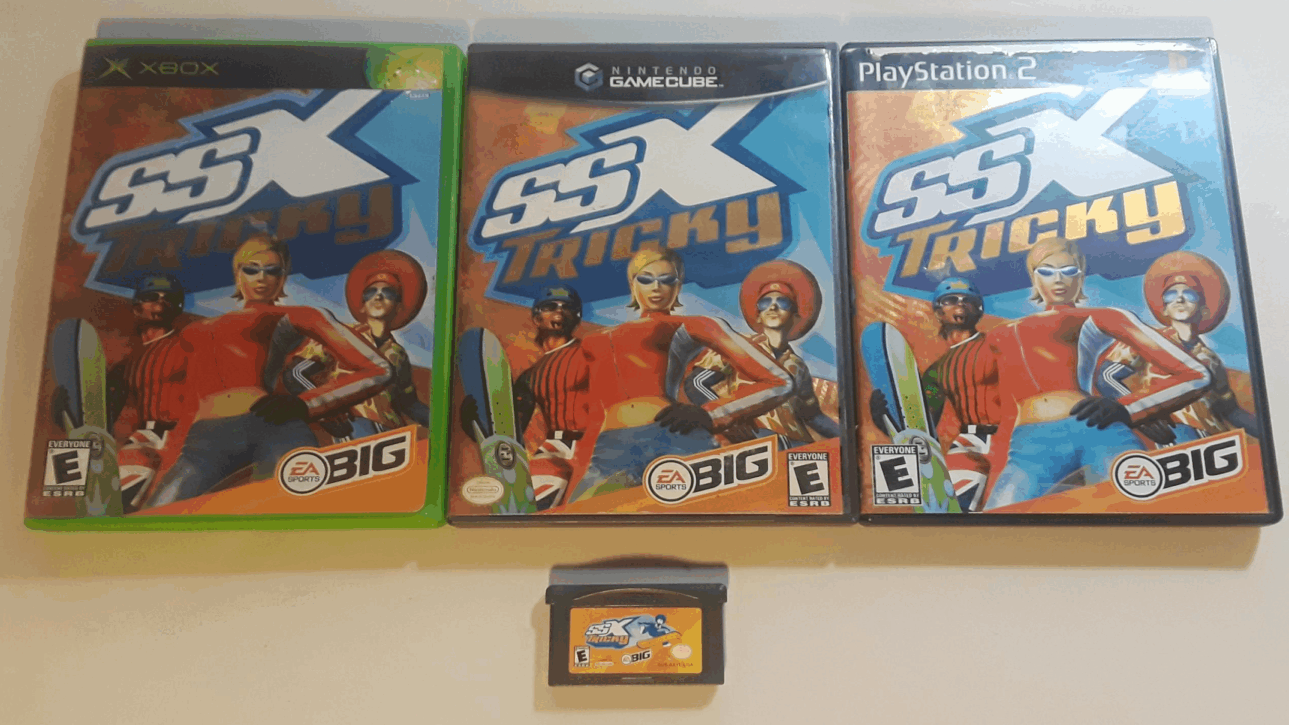 Four versions of the game SSX Tricky: Xbox, GameCube, and PlayStation 2 cases in a row with their Game Discs displayed, and a Game Boy Advance cartridge of the same game below them.
